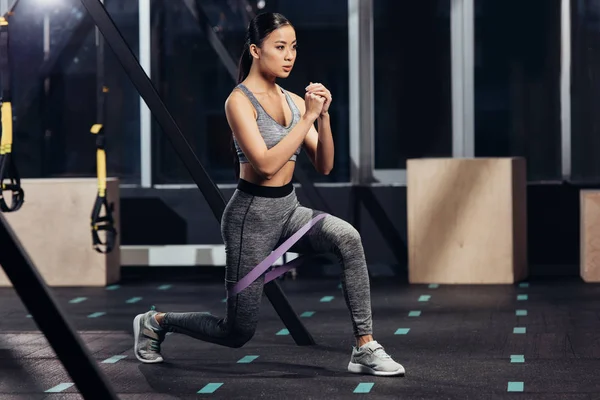 Attractive asian girl training with rubber resistance bands in modern gym — Stock Photo