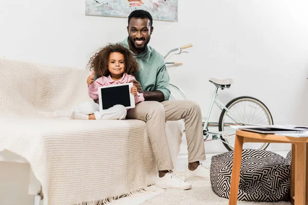 Afrikanisch-amerikanischer Vater und Tochter sitzen auf Couch und schauen in die Kamera — Stockfoto