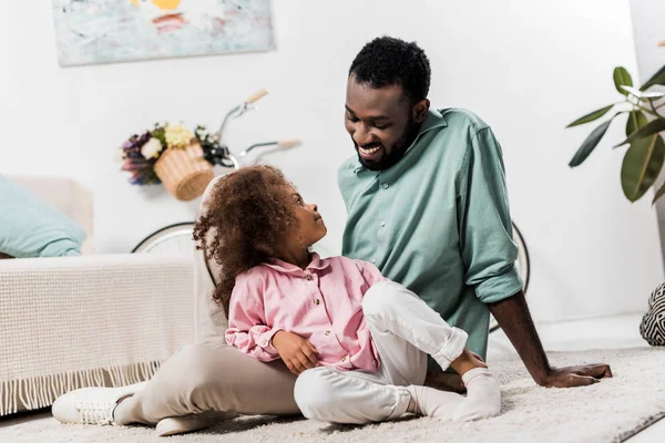 Афроамериканський батько і дочка комфортно сидять на підлозі — стокове фото