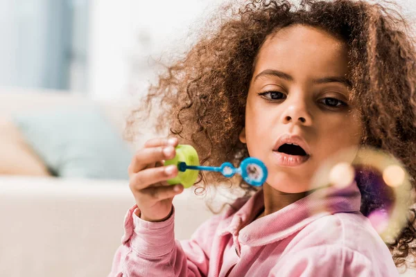 Lockiges afrikanisch-amerikanisches Kind pustet zu Hause Seifenblasen — Stockfoto