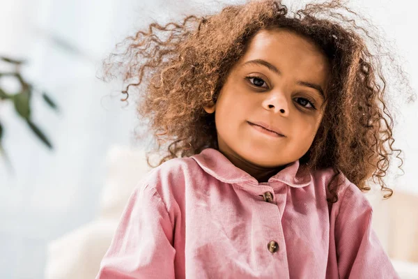 Schöne lockige afrikanisch-amerikanische Kind blickt in die Kamera und lächelt — Stockfoto