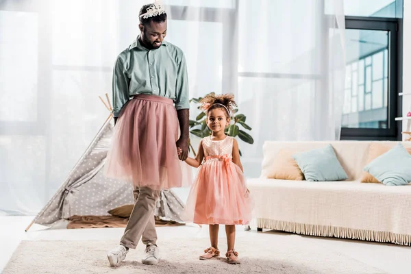 Happy african american father and adorable daughter dancing in pink tutu skirts — Stock Photo