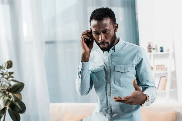 Upset african american man talking on smartphone — Stock Photo