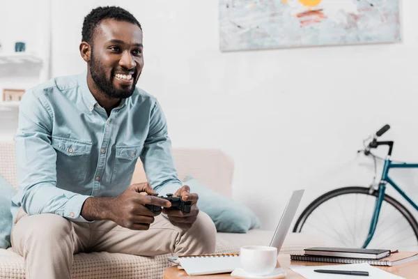 Uomo afroamericano che gioca al videogioco con joystick a casa — Foto stock