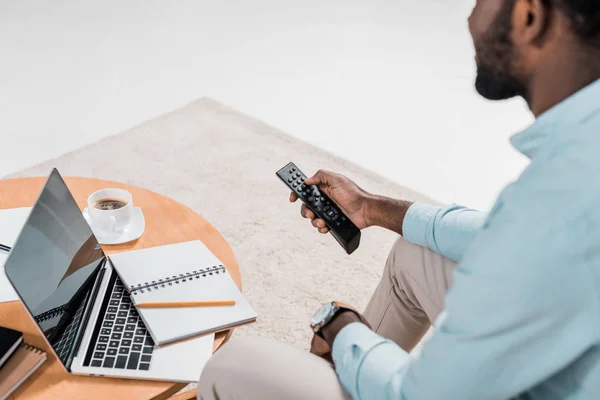 Cropped view of african american man using remote controller while sitting on couch — Stock Photo