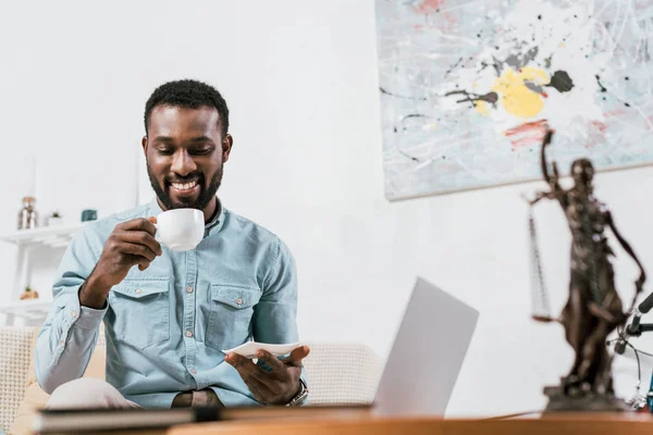 Homem americano africano bebendo café da xícara na sala de estar — Fotografia de Stock