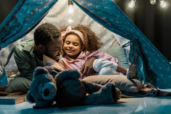 Afro-américaine papa et fille couché dans wigwam — Photo de stock