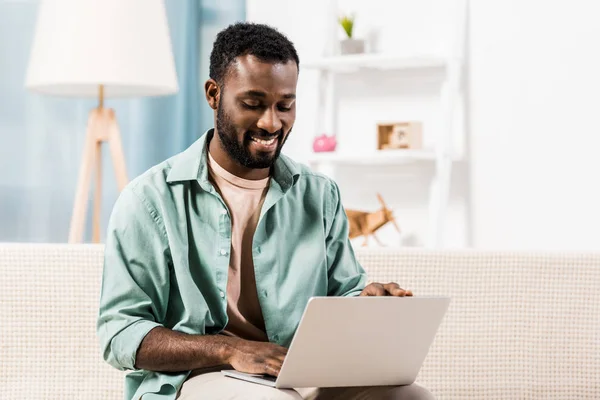 Homem americano africano trabalhando no laptop na sala de estar — Fotografia de Stock