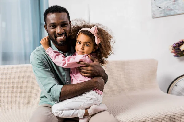 Père afro-américain étreignant fille dans le salon — Stock Photo