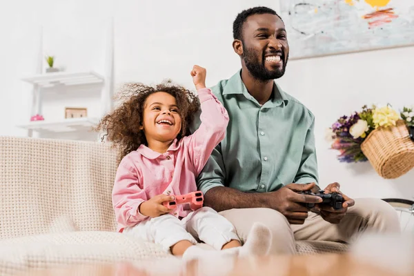 Afrikanisch-amerikanischer Vater lacht mit Tochter und spielt Videospiel im Wohnzimmer — Stockfoto