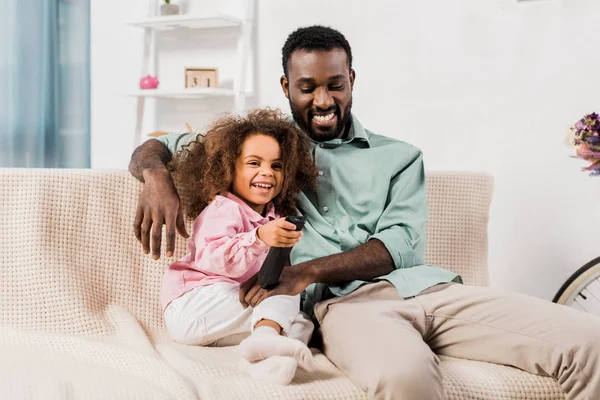 Africano americano papá y hija viendo tv juntos en sala de estar - foto de stock