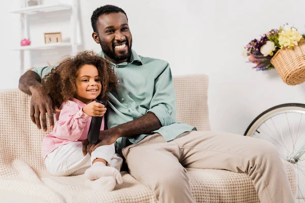 Африканский американец и дочь смотрят телевизор в гостиной — стоковое фото