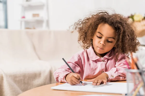 Grave enfant afro-américain dessin sur papier avec crayon de couleur dans le salon — Photo de stock