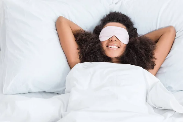 Menina americana africana feliz com os olhos cobertos pela venda de dormir na cama durante o horário da manhã em casa — Fotografia de Stock