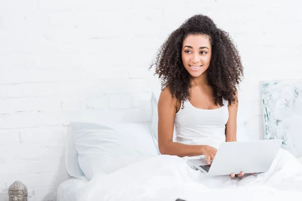 Menina encaracolado usando laptop na cama durante o tempo da manhã em casa — Fotografia de Stock