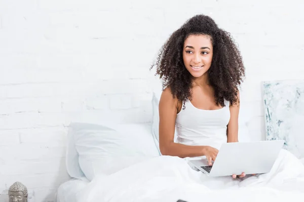 Ragazza riccia utilizzando il computer portatile a letto durante il mattino a casa — Foto stock