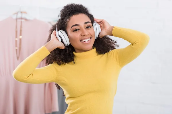 Positive femme afro-américaine écouter de la musique dans les écouteurs — Photo de stock