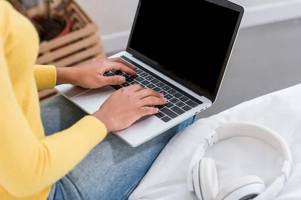 Vista parcial del freelancer femenino que trabaja en el ordenador portátil con pantalla en blanco en casa - foto de stock