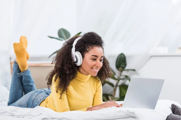 Atractiva freelancer femenina en auriculares que trabajan en el ordenador portátil en la oficina en casa - foto de stock