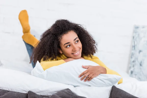 Мечтательный красивый африканский американец молодая женщина лежит в постели и смотрит в сторону — стоковое фото