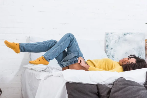 Стильна афроамериканська дівчина надягає джинси в спальню вдома — стокове фото