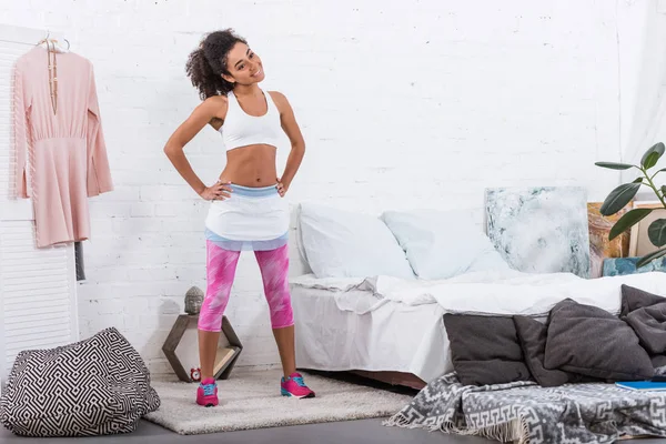 Mujer afroamericana feliz haciendo ejercicio durante la mañana en el dormitorio en casa - foto de stock