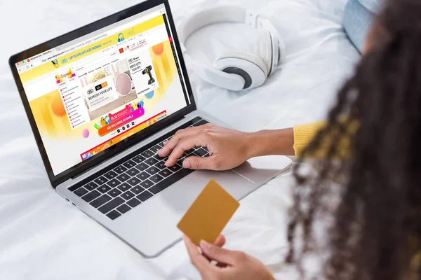 Cropped image of woman holding credit card and using laptop with aliexpress on screen — Stock Photo