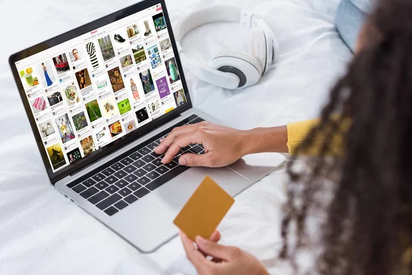 Cropped image of woman holding credit card and using laptop with pinterest on screen — Stock Photo