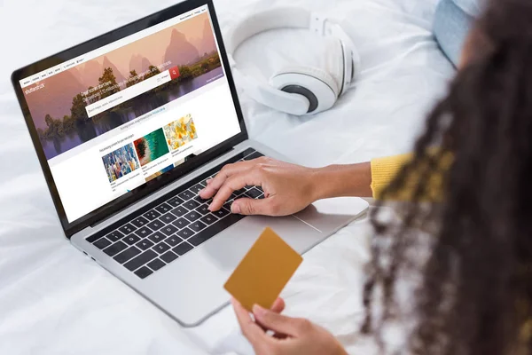 Cropped image of woman holding credit card and using laptop with shutterstock on screen — Stock Photo