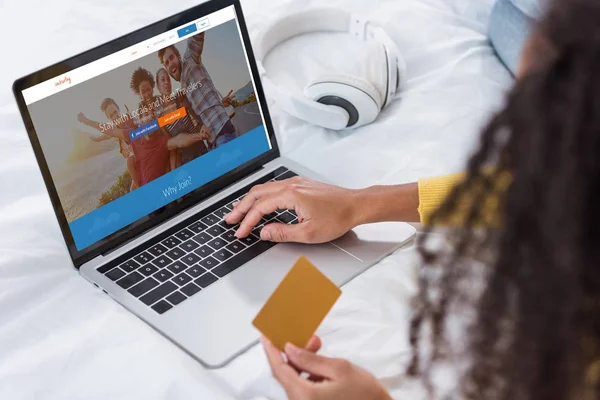 Imagem cortada de mulher segurando cartão de crédito e usando laptop com couchsurfing na tela — Fotografia de Stock