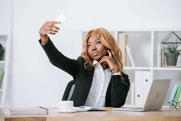 Confiada mujer de negocios afroamericana tomando selfie en teléfono inteligente - foto de stock