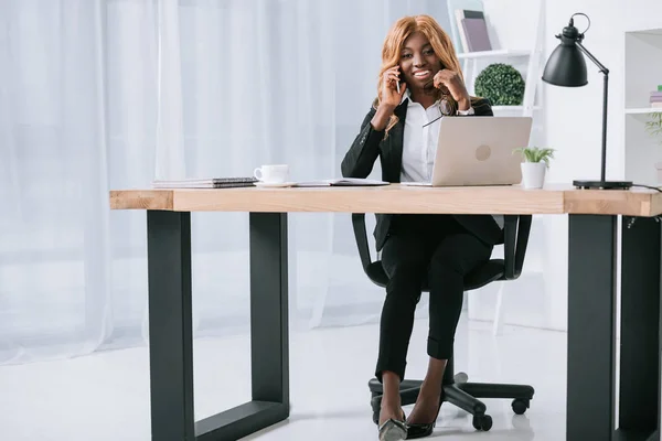 Beautiful african american businesswoman talking on smartphone in office — Stock Photo