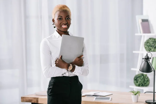 Cheerful african american businesswoman holding laptop in hands — Stock Photo