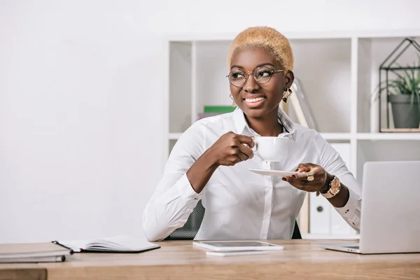 Афро-американських бізнес-леді з коротким волоссям, сидячи в окулярах і тримає Кубок — стокове фото