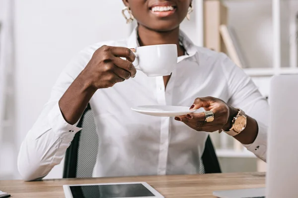 Vista cortada de mulher afro-americana segurando xícara de café — Fotografia de Stock