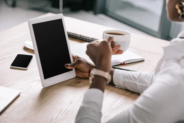 Vue recadrée de femme afro-américaine tenant tasse et tablette numérique avec écran blanc — Photo de stock