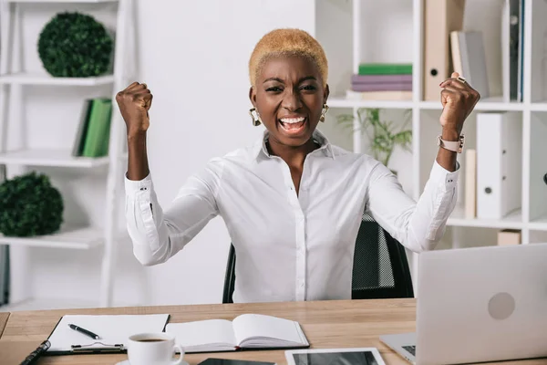 Feliz mulher de negócios afro-americana sorrindo e mostrando sinal de vitória — Stock Photo