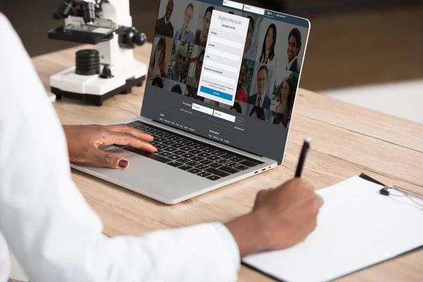 Cropped view of african american doctor using laptop with linkedin website on screen — Stock Photo
