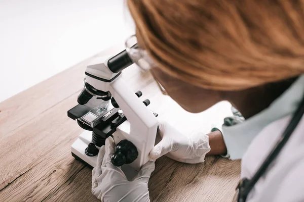 Vista cortada do cientista americano africano fêmea olhando através do microscópio — Fotografia de Stock