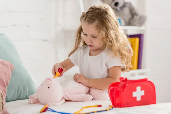 Criança adorável examinando brinquedo de coelho na sala de crianças — Fotografia de Stock