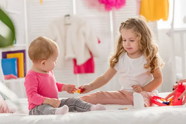 Irmãs adoráveis brincando com kit de primeiros socorros na cama na sala de crianças — Fotografia de Stock