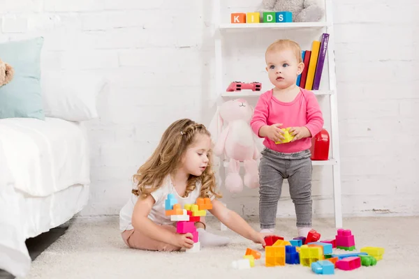 Прелестные сестры играют с конструктором в детской комнате — стоковое фото