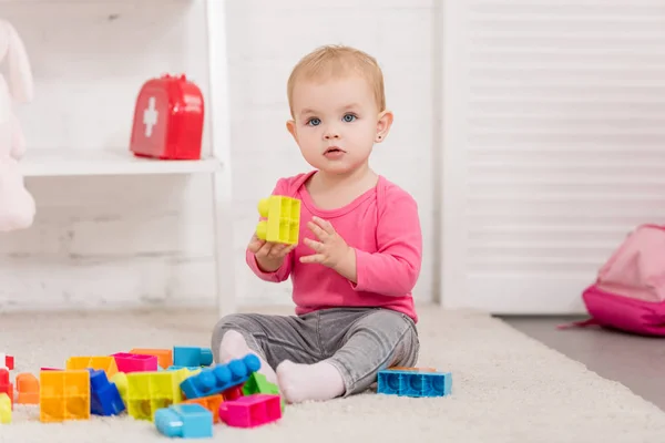 Criança adorável brincando com construtor no tapete na sala de crianças — Fotografia de Stock