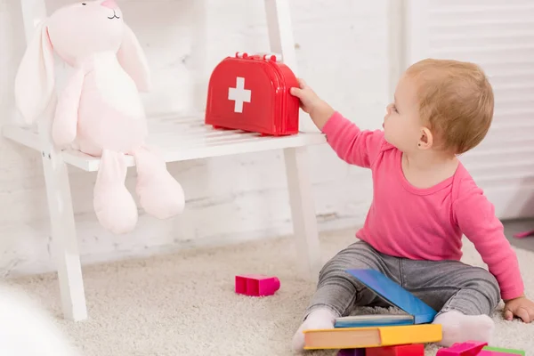 Adorable kid taking first aid kit in children room — Stock Photo