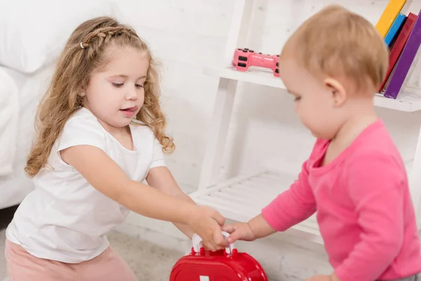 Entzückende Schwestern mit Verbandskasten im Kinderzimmer — Stockfoto