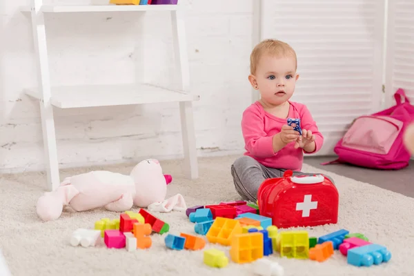 Criança adorável brincando com kit de primeiros socorros na sala de crianças — Fotografia de Stock