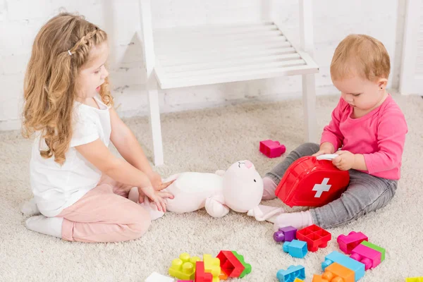 Vista ad alto angolo di adorabili sorelle che giocano con i giocattoli nella stanza dei bambini — Foto stock