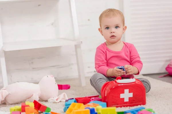 Adorabile bambino che gioca sul tappeto e guarda in alto nella stanza dei bambini — Foto stock