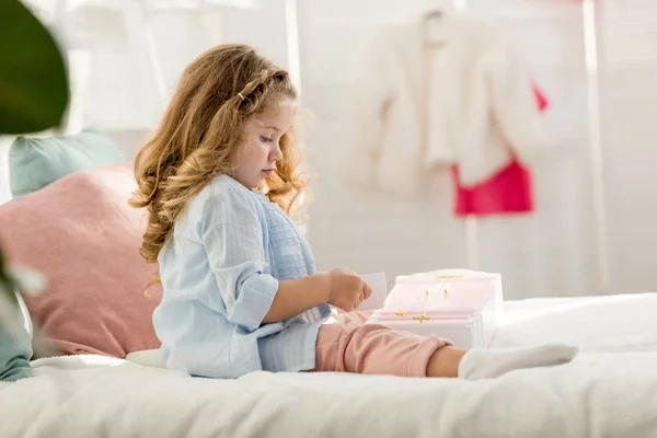 Vue latérale de l'adorable enfant jouant sur le lit dans la chambre des enfants — Photo de stock