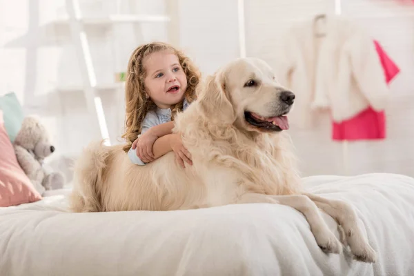 Adorable kid and dog lying on bed in children room — Stock Photo